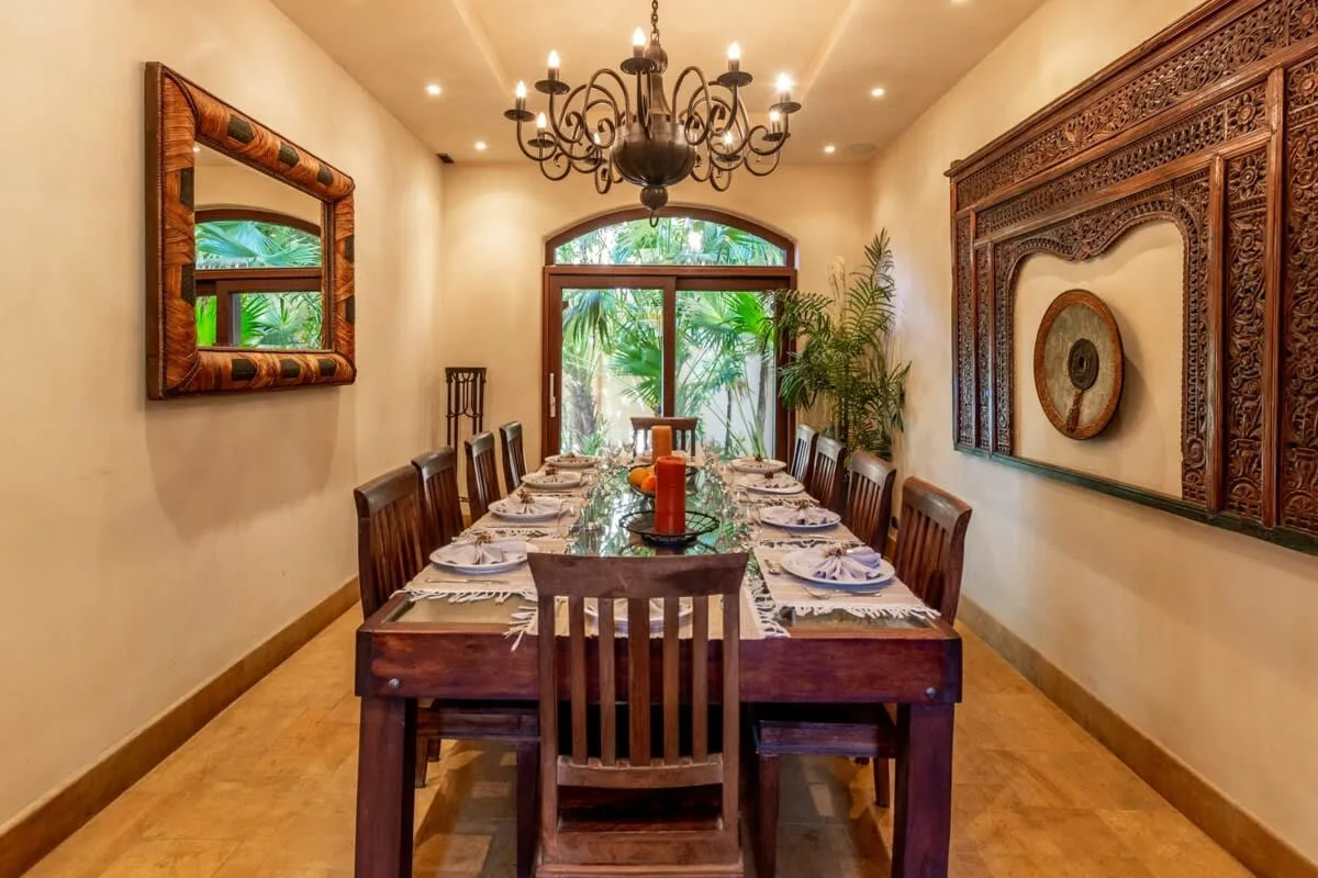 A dining room with a long table set beneath a chandelier.