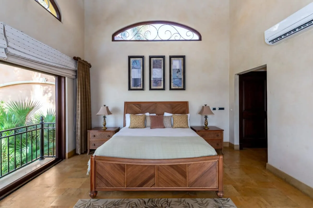 A bedroom with a wooden bed, bedside tables, and a large window.