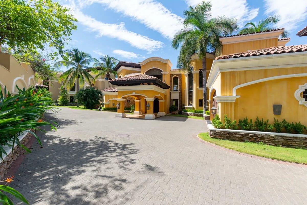 A large yellow building with an arched entrance stands beside a paved driveway.