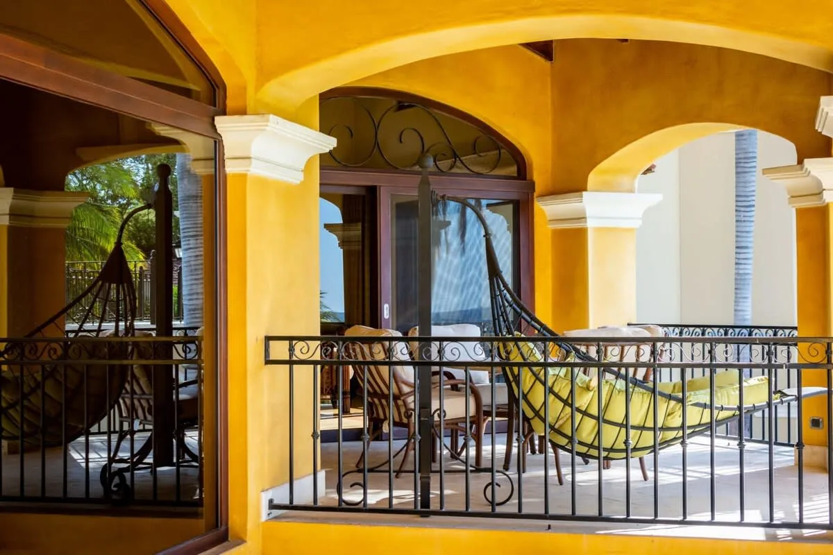 A covered balcony with arched openings, metal railings, and outdoor seating.