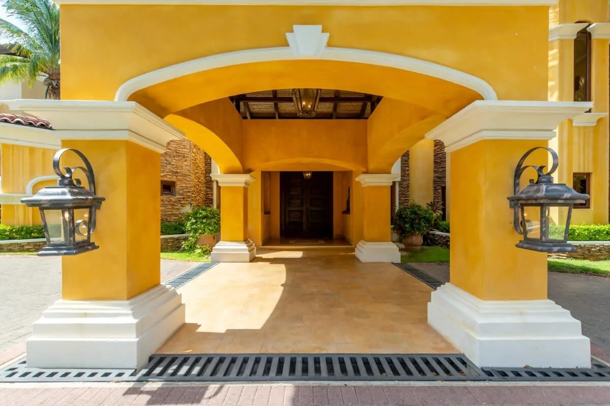 A yellow stucco entrance with a broad archway and dark double doors.