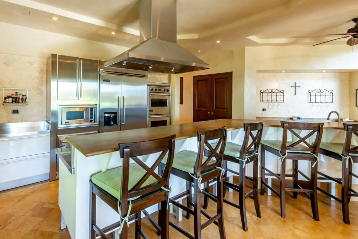 A spacious kitchen with a central island and wooden seating.