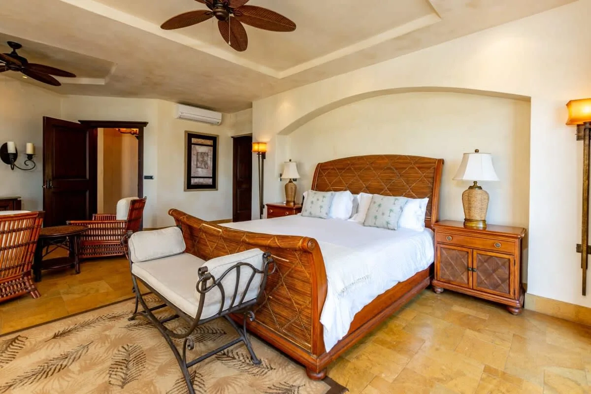 A bedroom with a wooden bed, white bedding, and a seating area.
