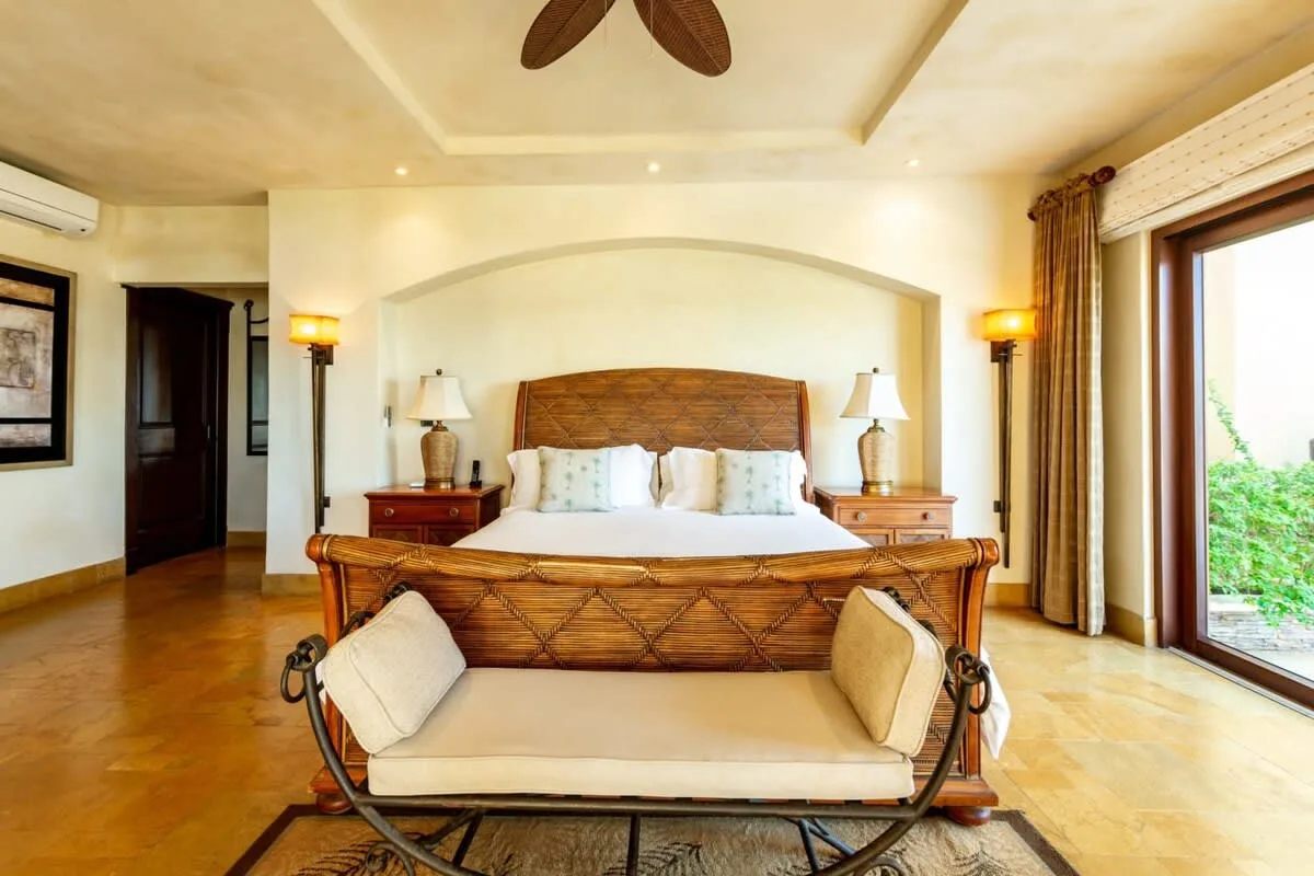 A bedroom with a large bed and a cushioned bench at its foot.