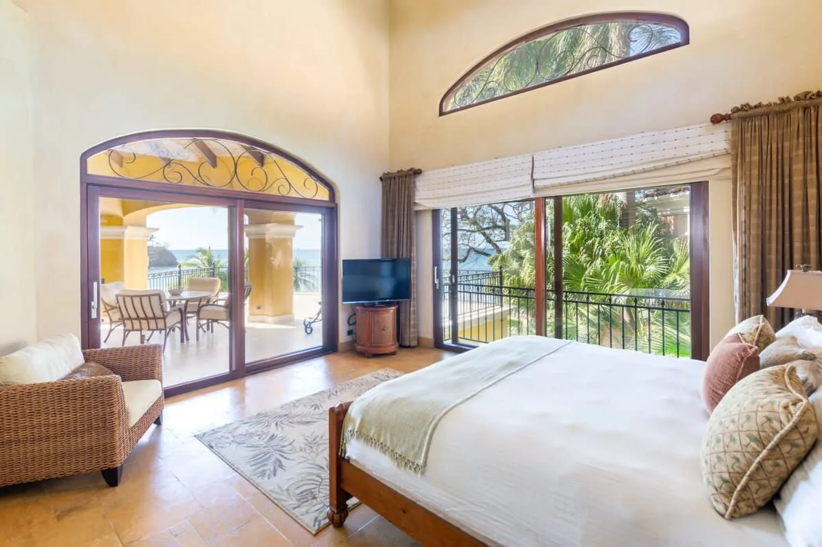 A bright bedroom with a large bed and glass doors opening onto a balcony.