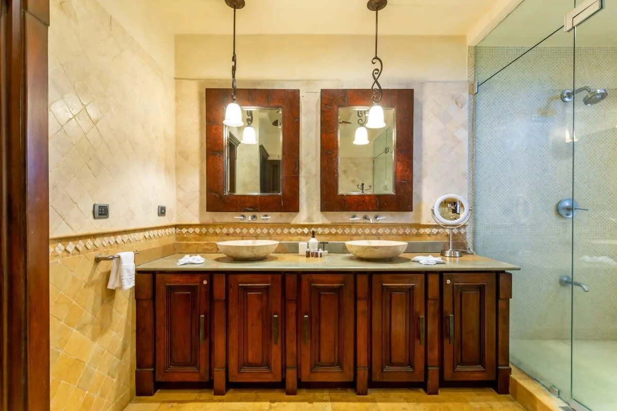 A bathroom vanity with two sinks, mirrors, and a glass shower.