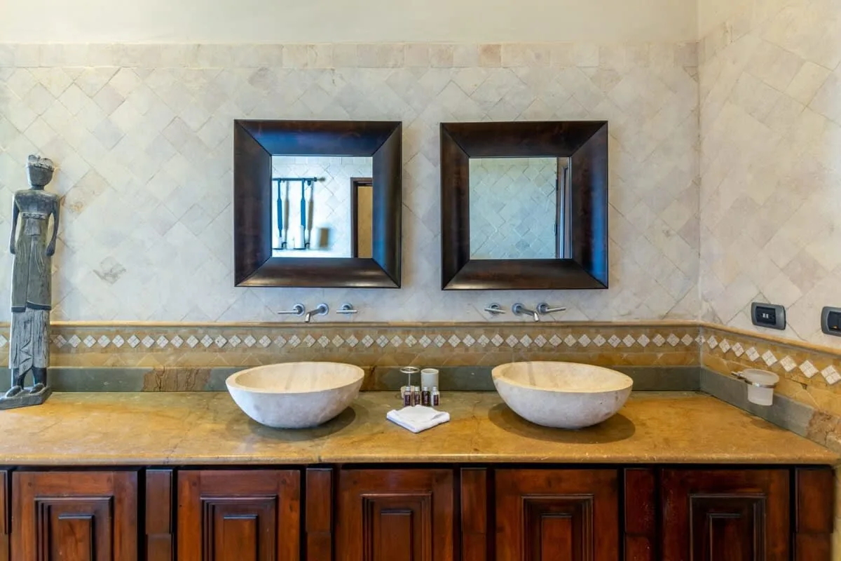 A bathroom vanity with two vessel sinks, framed mirrors, and wooden cabinetry.