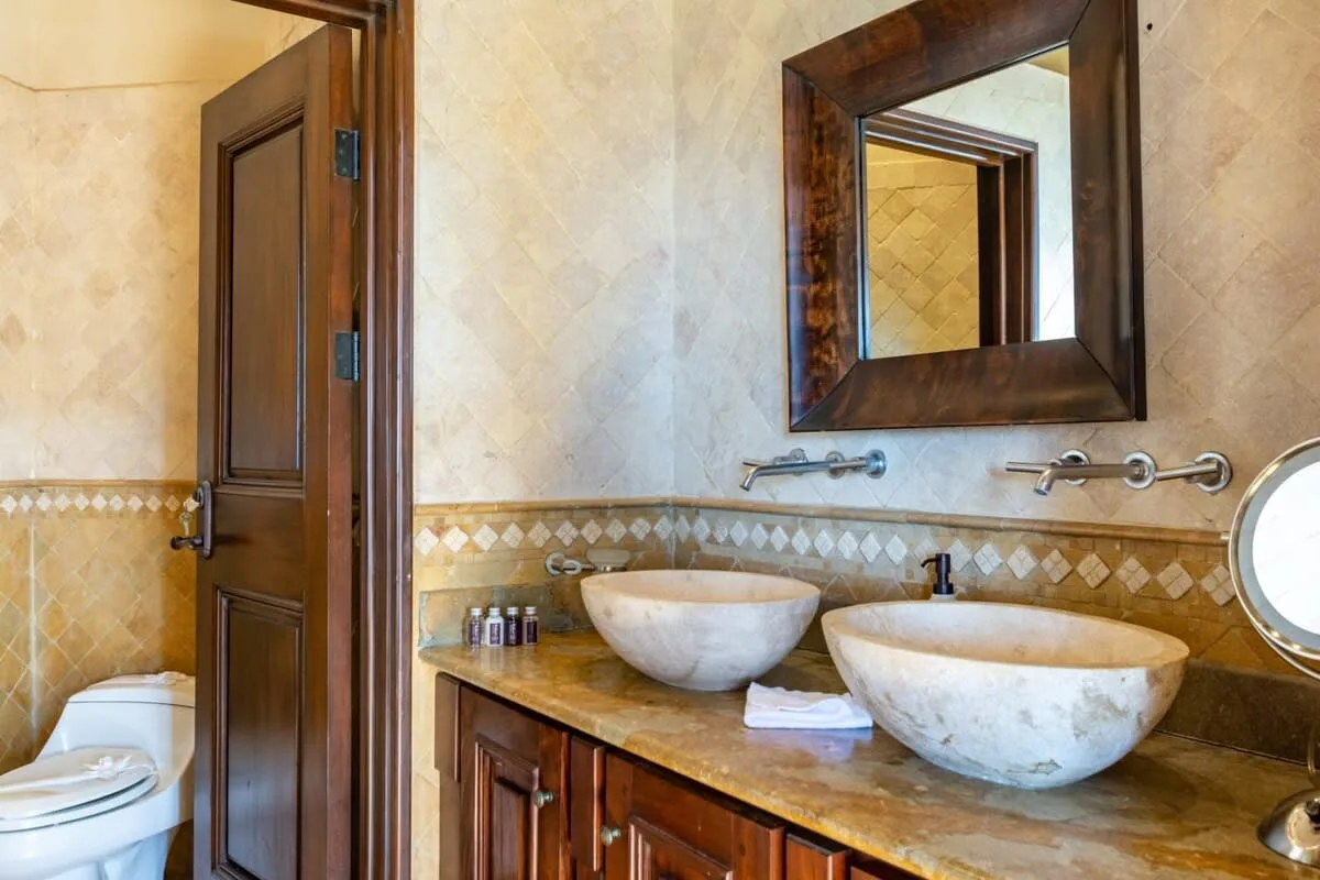 A bathroom vanity with two vessel sinks, a wall mirror, and an open doorway.