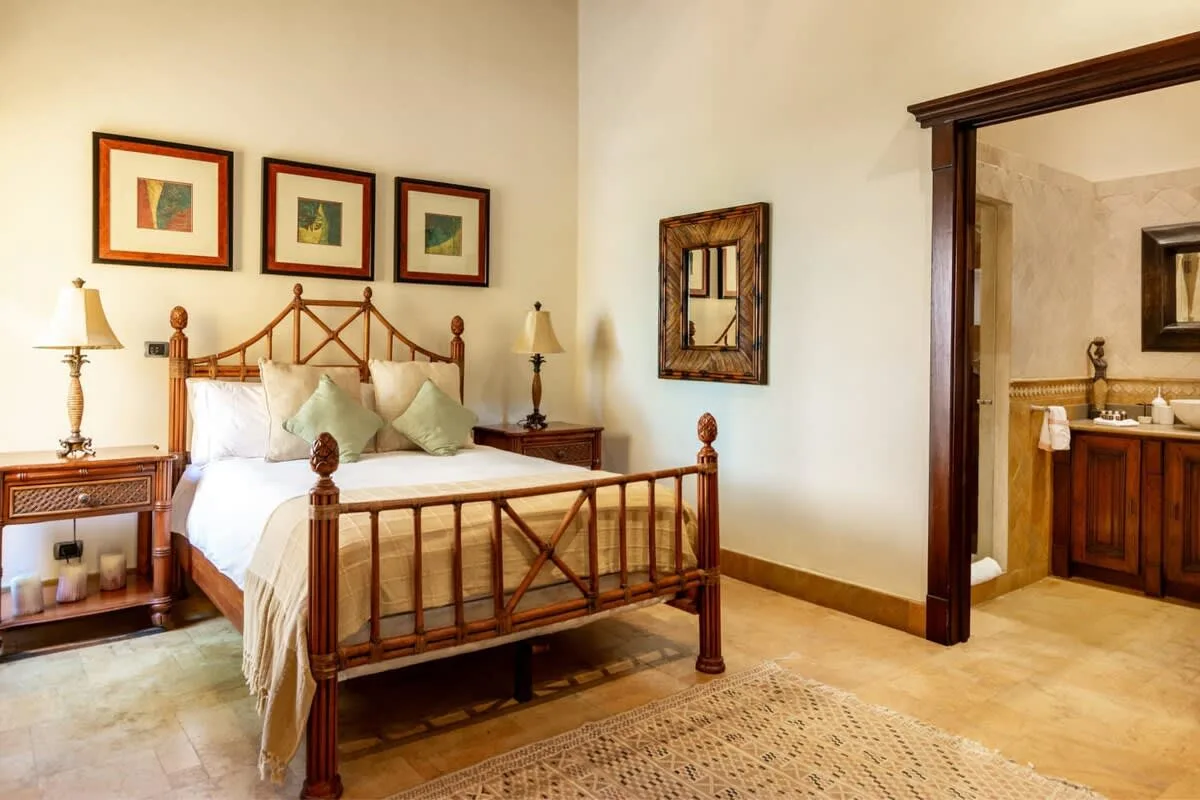Bedroom with a wooden bed and an adjoining bathroom doorway.