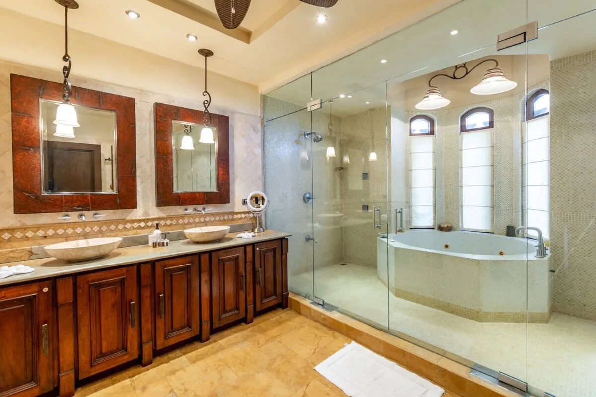 A spacious bathroom with a long wooden vanity, glass shower, and bathtub.