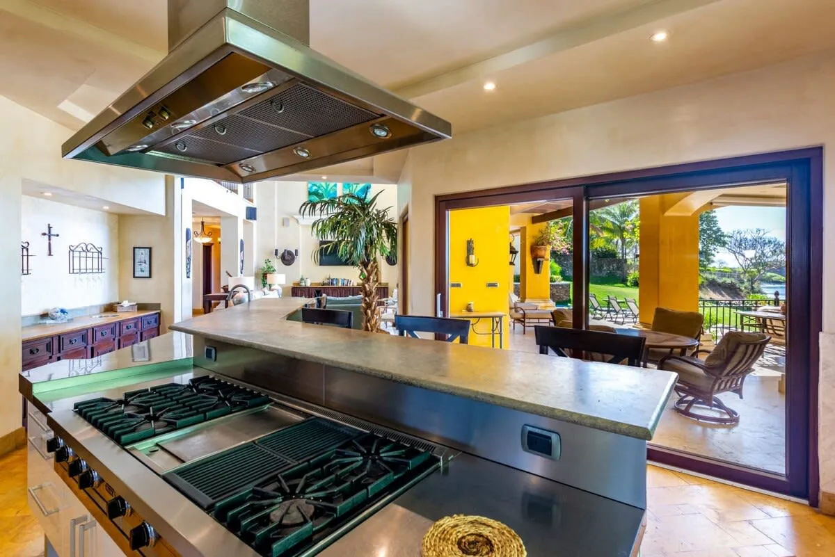 A spacious kitchen opens through wide glass doors to a sunny patio with seating.