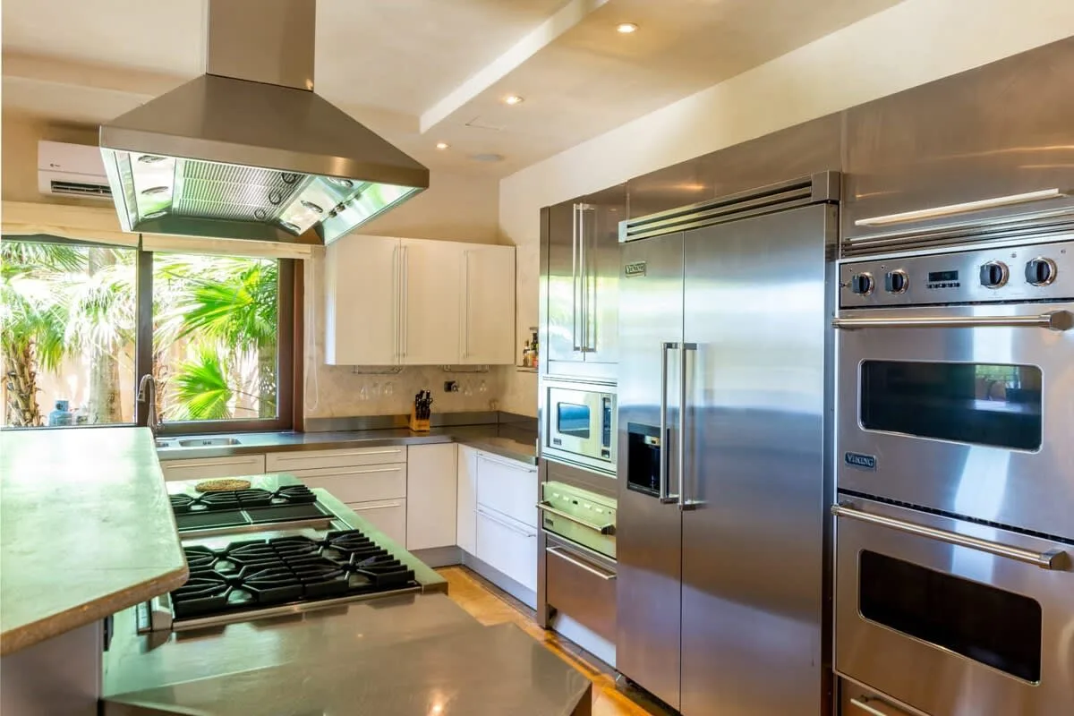 A modern kitchen with a gas cooktop, stainless steel refrigerator, and built-in ovens.