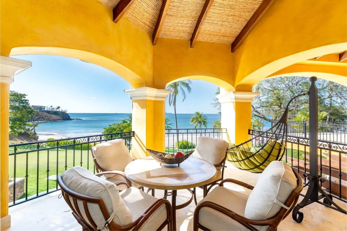 A covered balcony with seating and a view of the ocean.