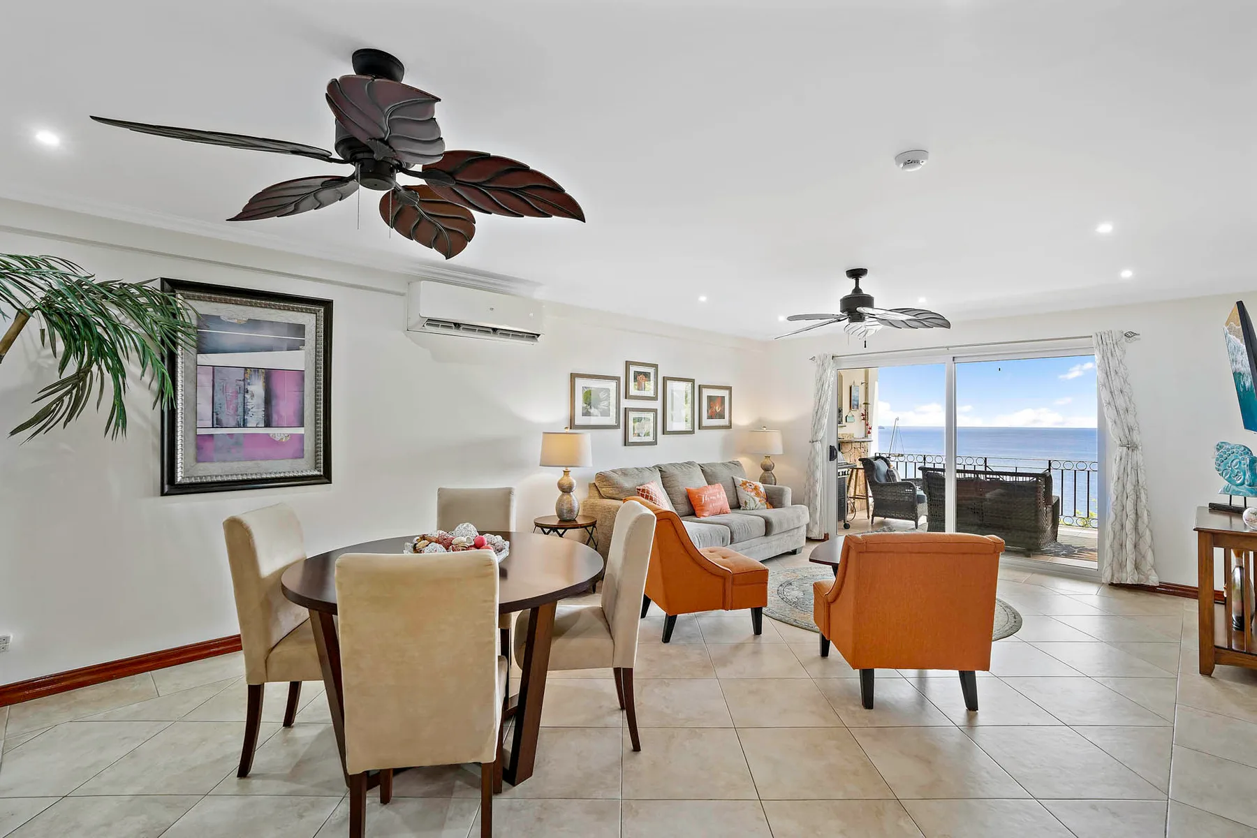 A bright living and dining area opens onto a balcony overlooking the ocean.