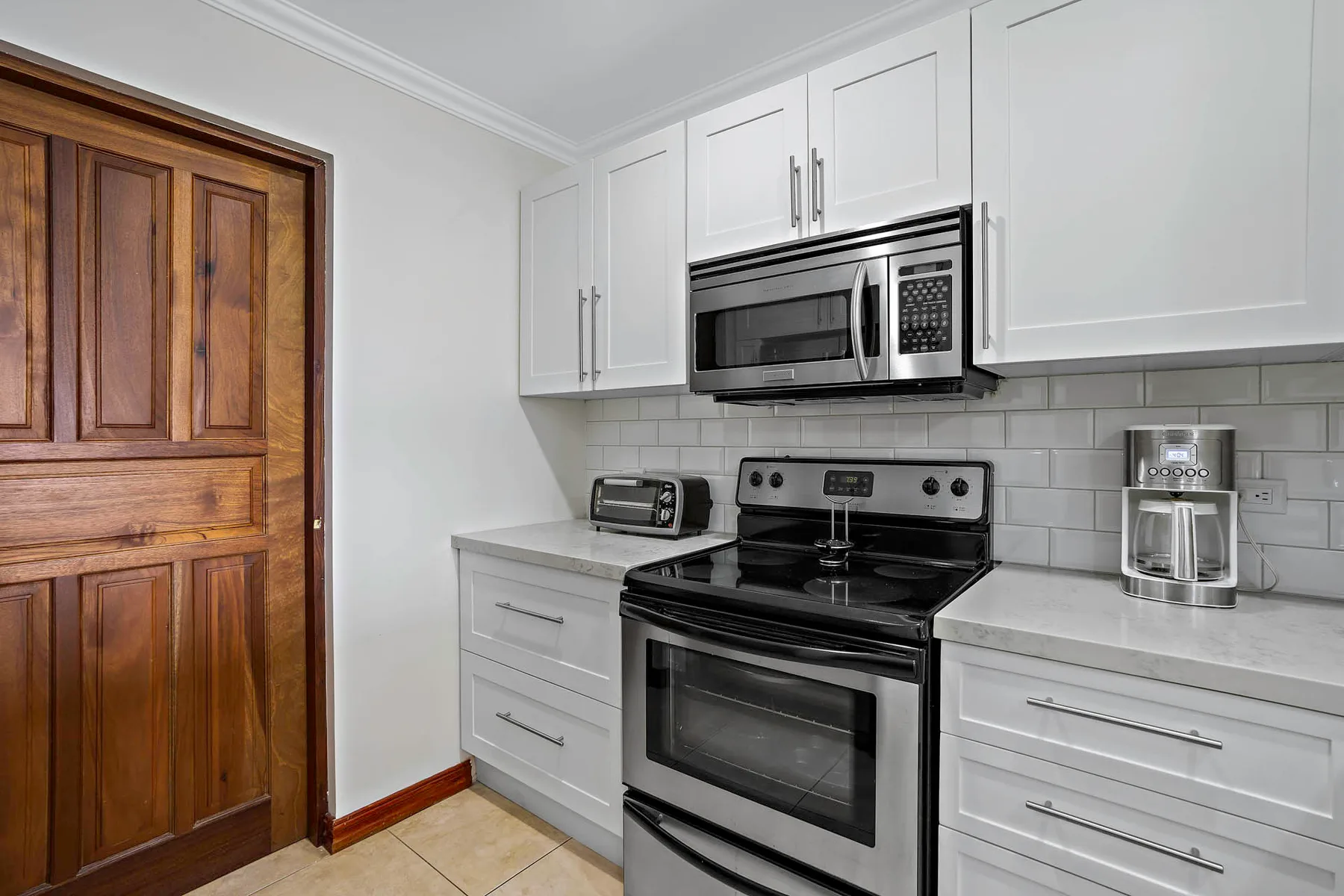 A kitchen with a black range and microwave between white cabinets.