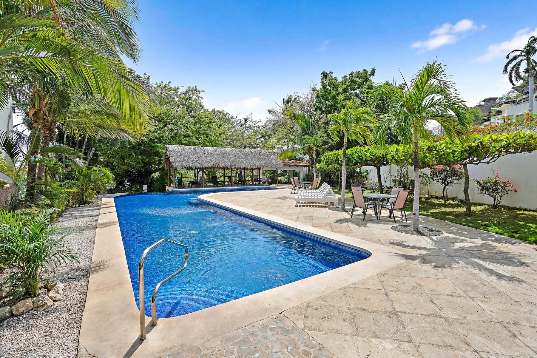 Shared amenity: An outdoor swimming pool is surrounded by palm trees and patio seating.