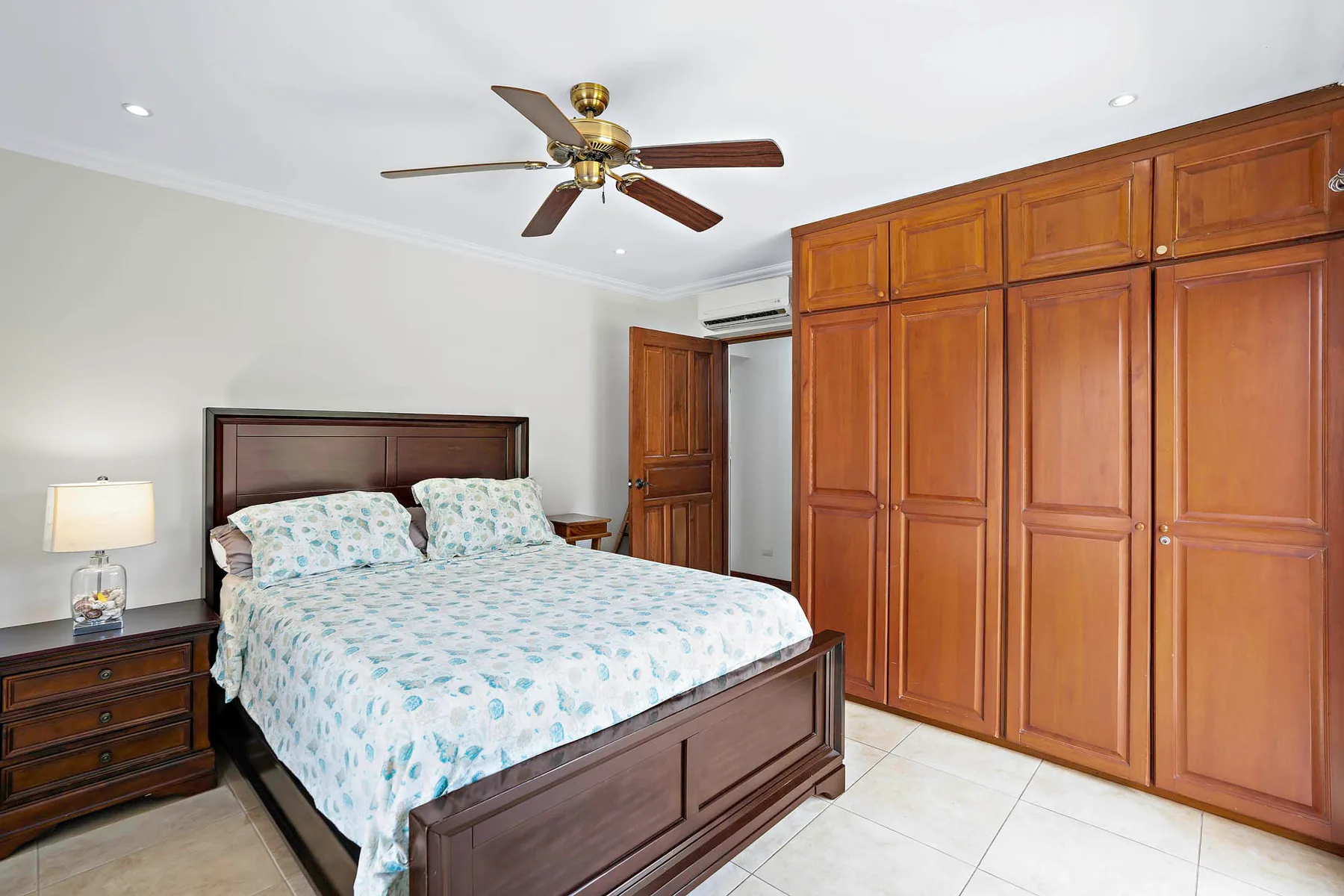 A bedroom with a bed beside a wall of wooden wardrobes.