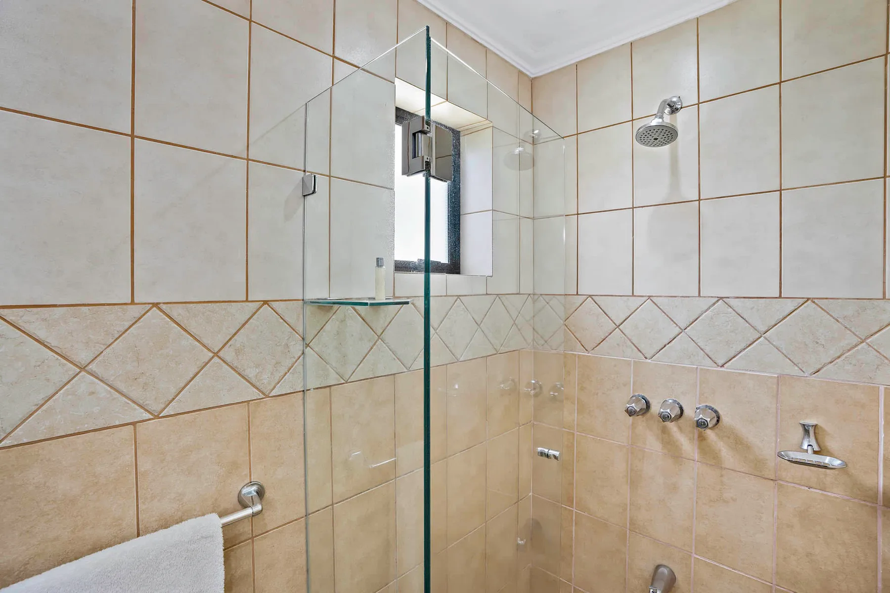 A tiled shower area with glass panels and wall-mounted fixtures.
