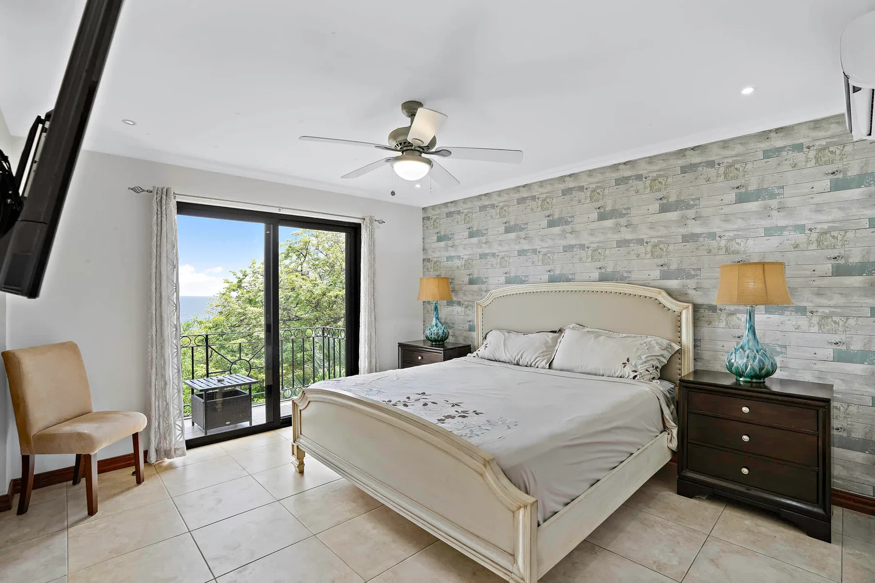 A bedroom with a bed, bedside tables, and glass doors opening to a balcony.