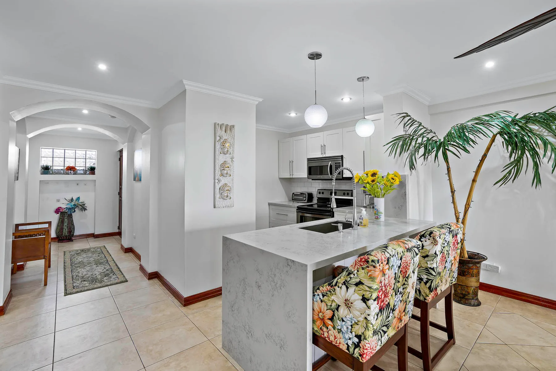 A bright kitchen and dining area with a large island and floral-patterned seating.