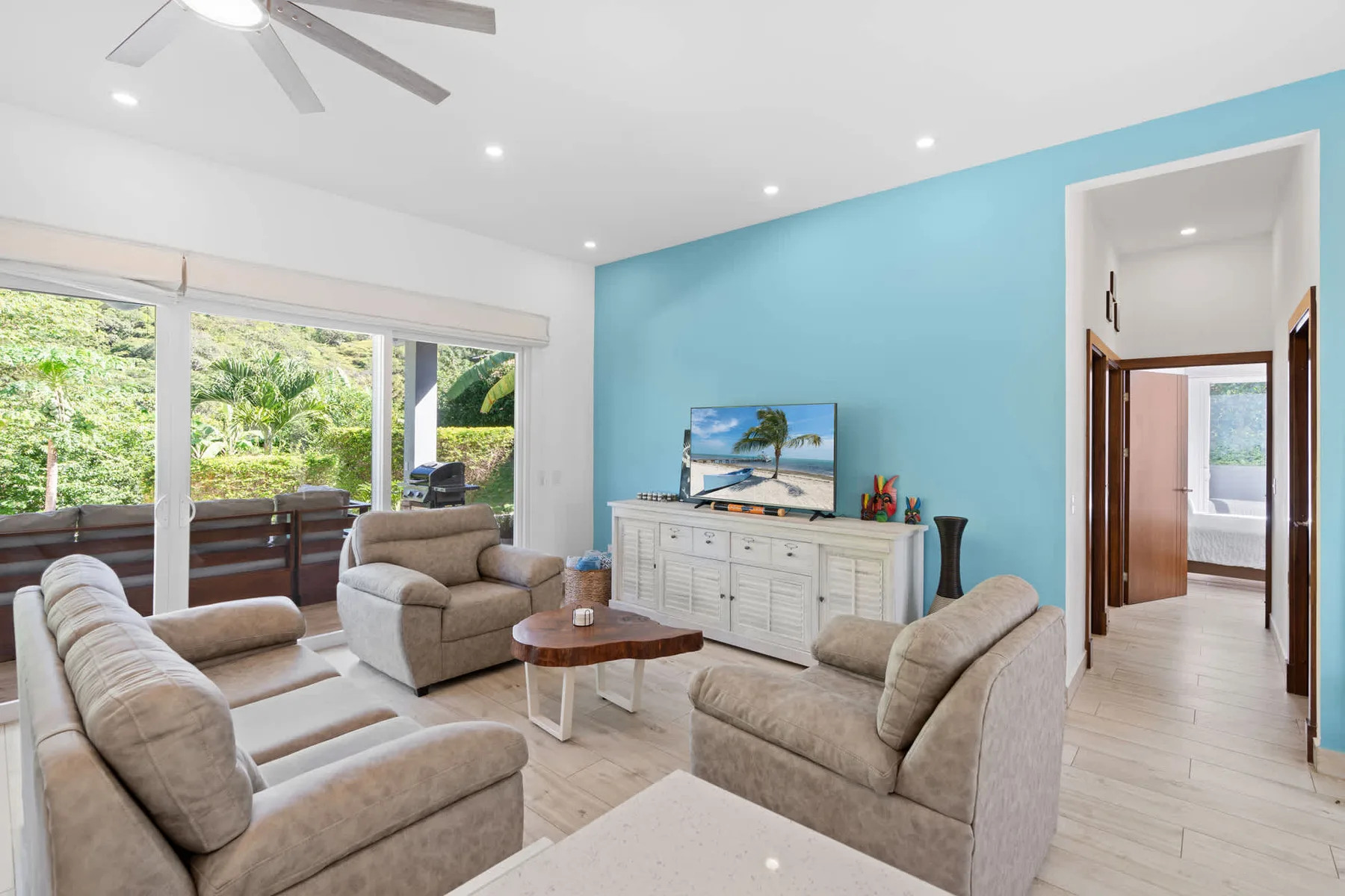 A bright living room with seating arranged around a coffee table and television.