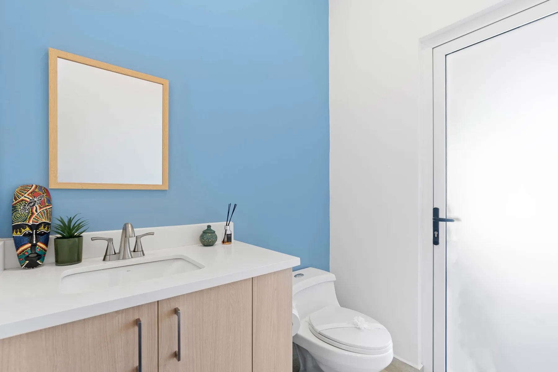 A bathroom with a vanity, sink, and toilet beside a white door.