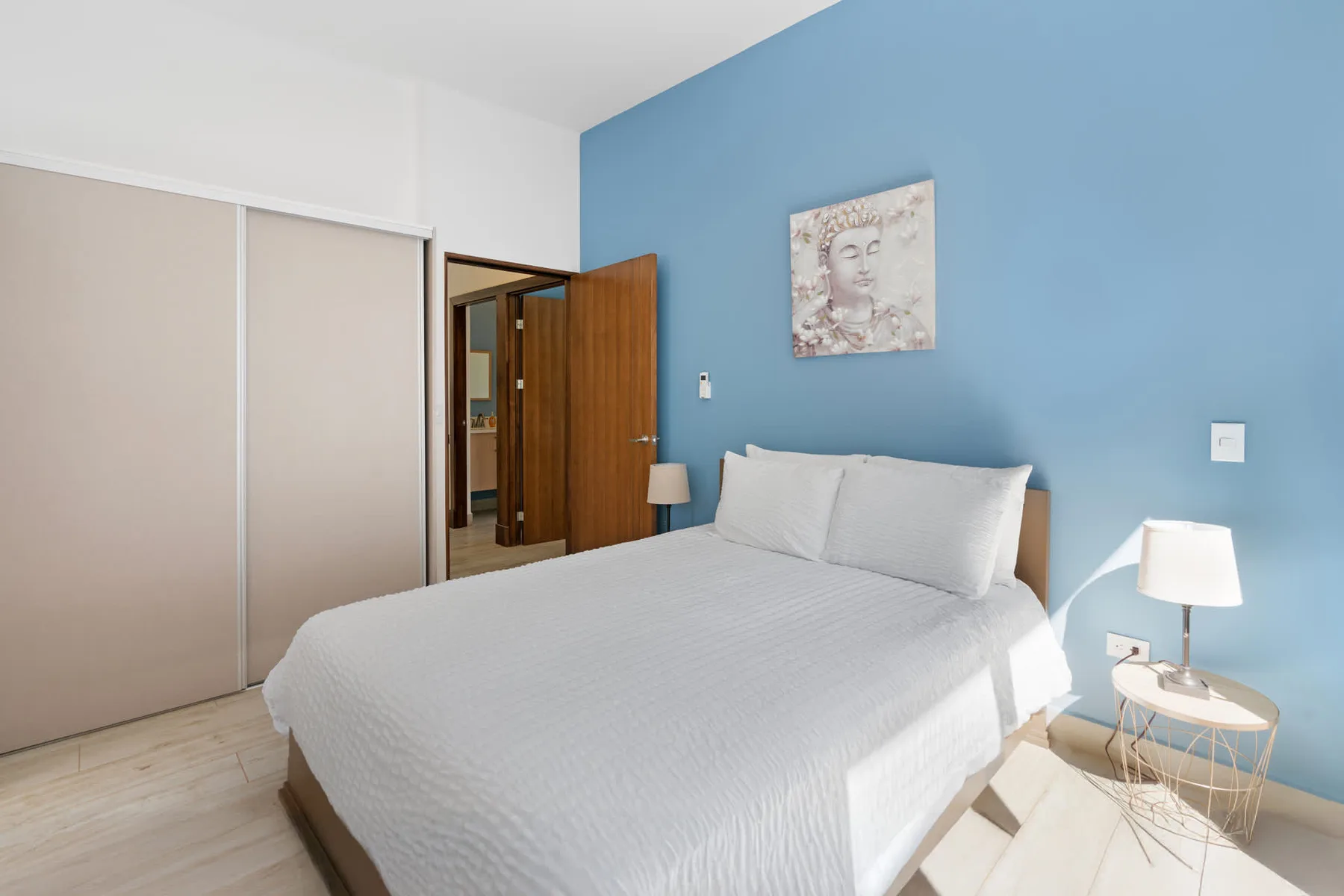 A bedroom with a bed against a blue wall and a sliding-door closet.