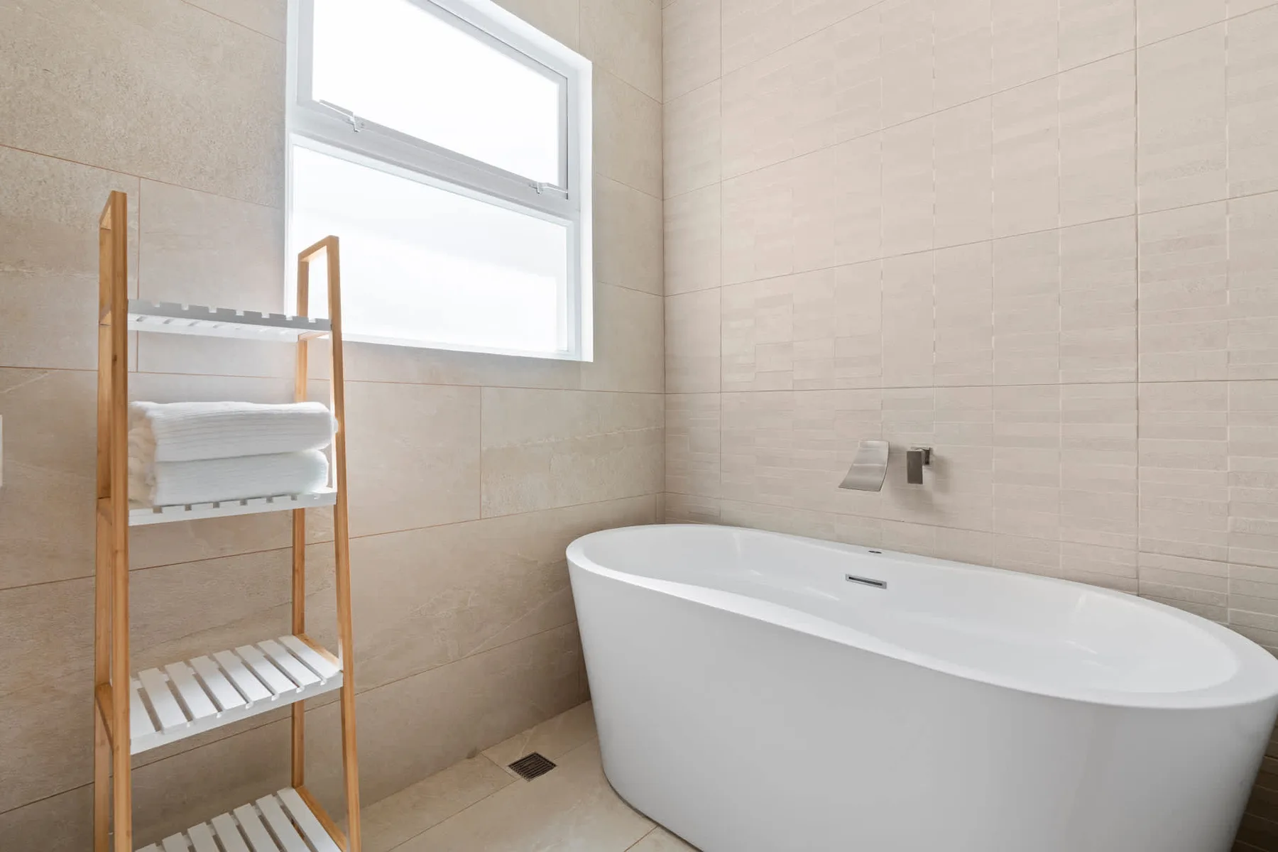 A bright bathroom features a freestanding bathtub and a window.