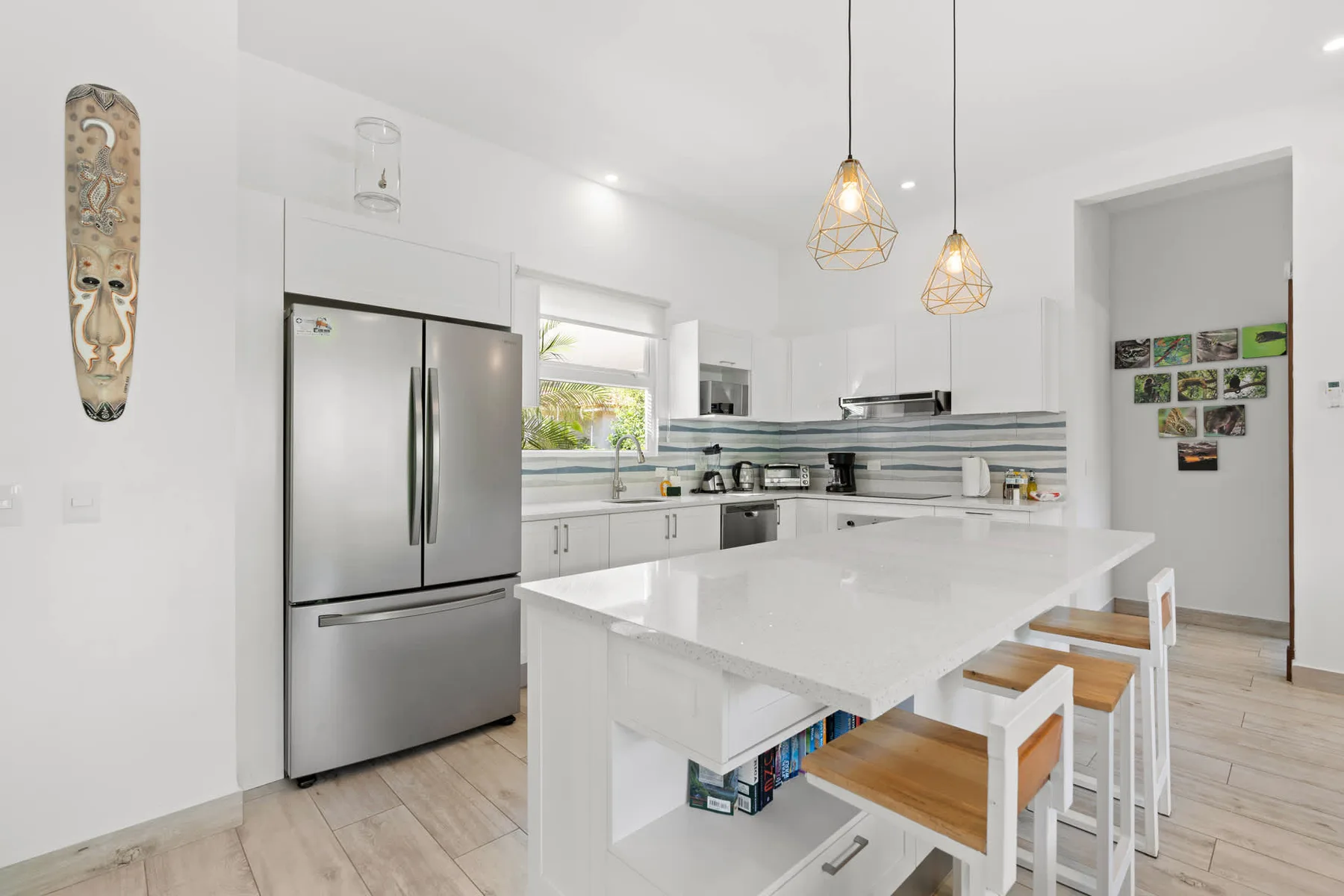 A bright white kitchen with a large island and pendant lights.