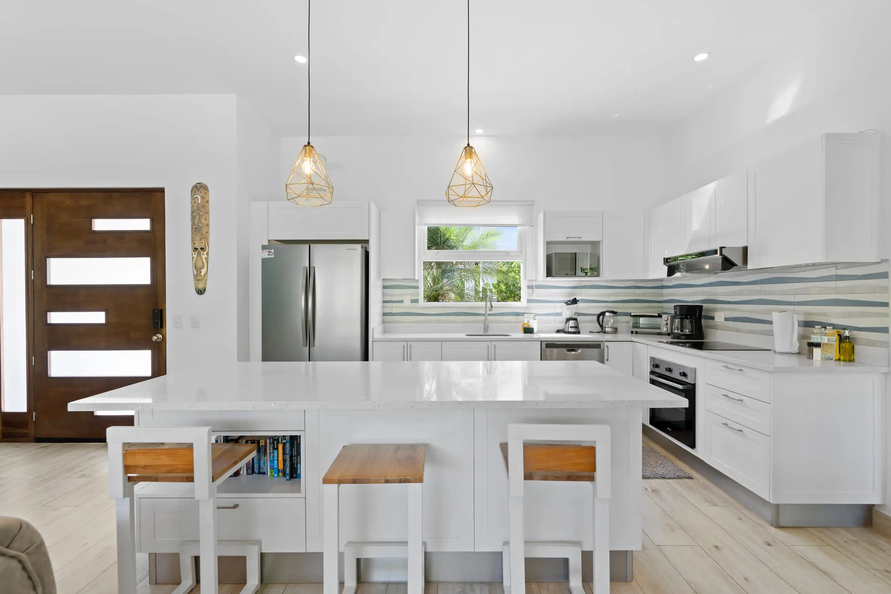 A bright modern kitchen with a large island and pendant lights.