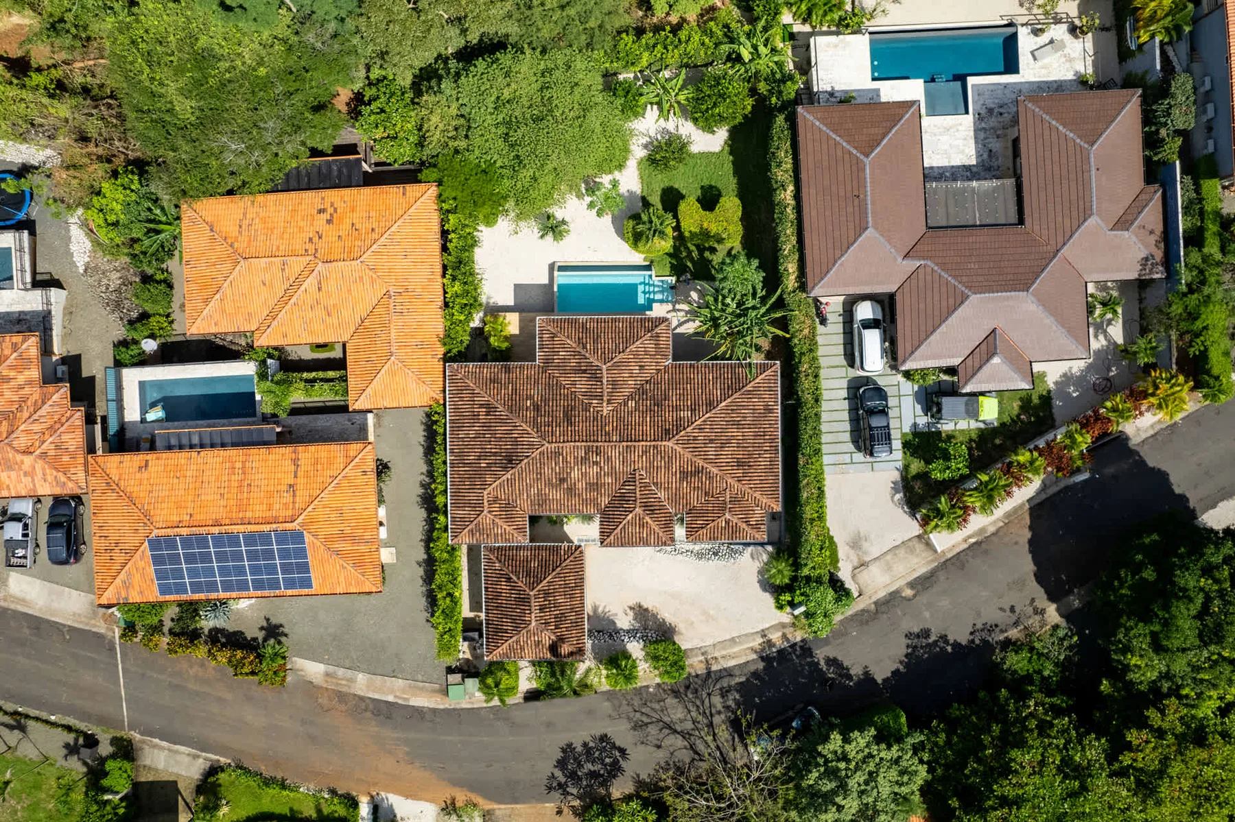 Aerial view of several homes with swimming pools and surrounding greenery.