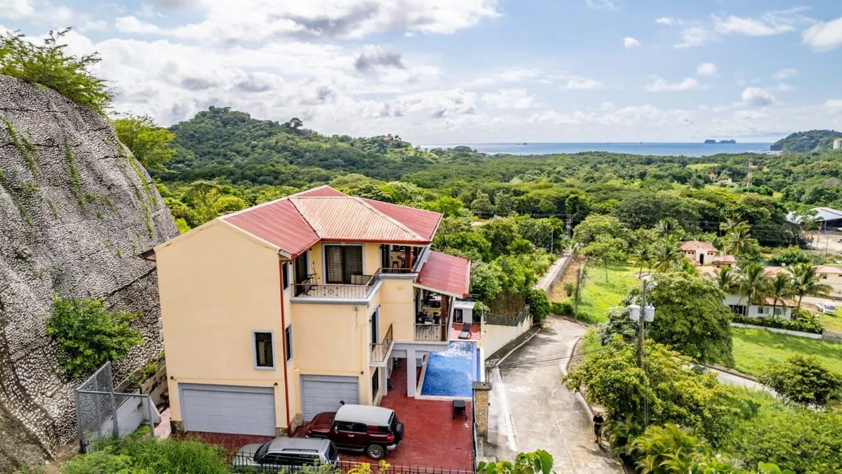 Shared amenity: A hillside building overlooks a road, dense greenery, and the distant ocean.