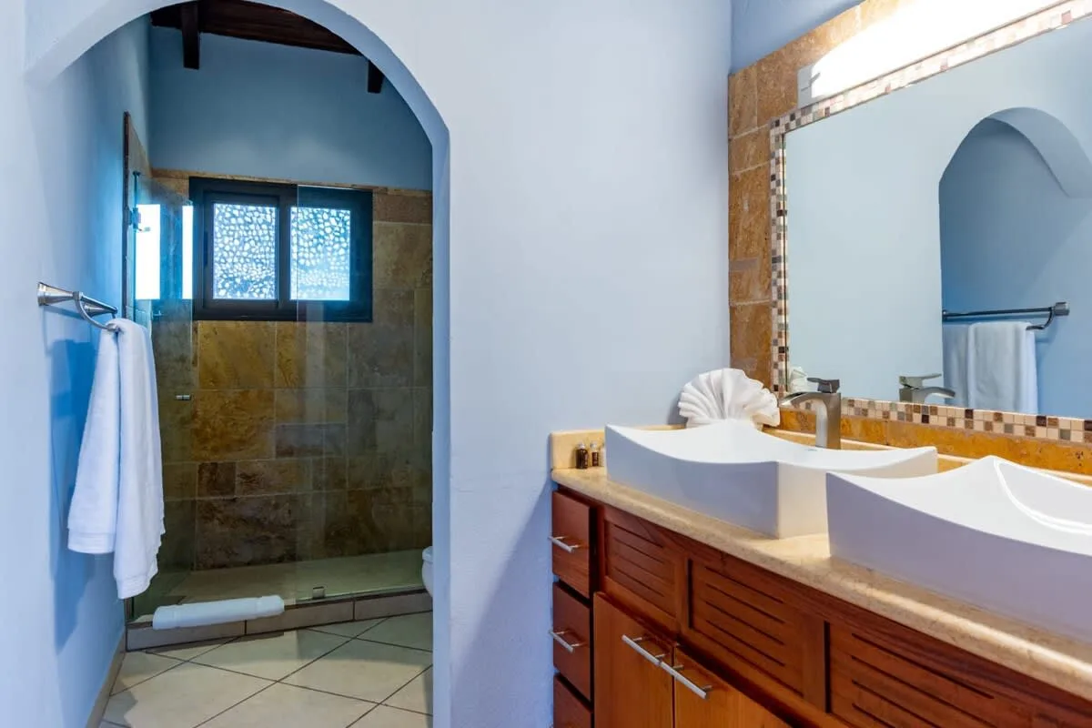 A bathroom with a tiled shower and a double sink vanity.