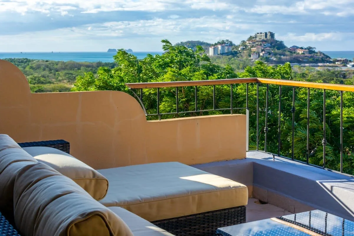A terrace seating area overlooks green hills and the ocean.