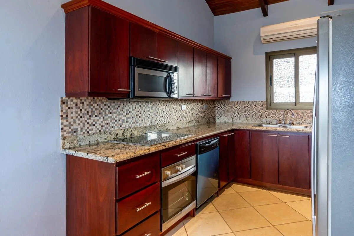A kitchen with dark wood cabinets, a tiled backsplash, and a window.