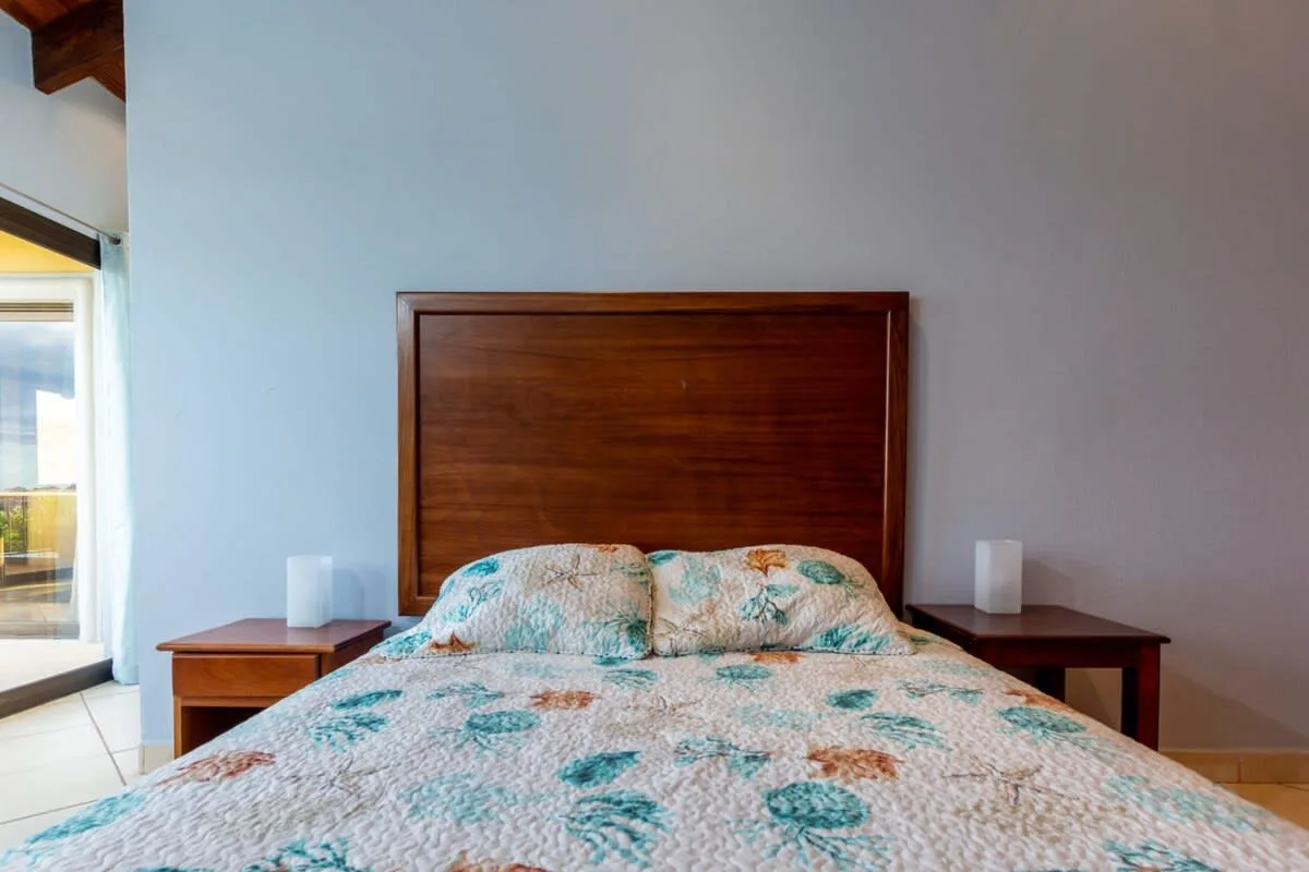 A bedroom with a bed covered in a floral-patterned quilt.