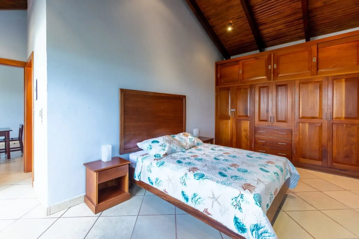 A bedroom with a bed beside built-in wooden cupboards.