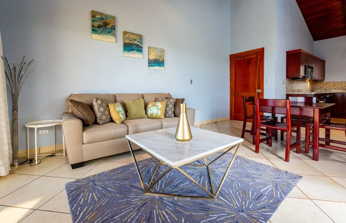 A living room with a beige sofa, a coffee table, and a dining area.