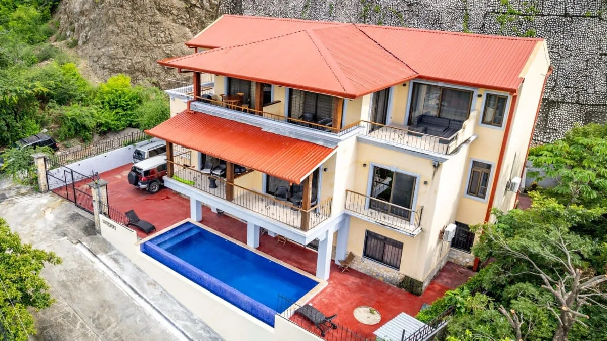 Shared amenity: A multi-level house with red roofs overlooks a blue swimming pool.