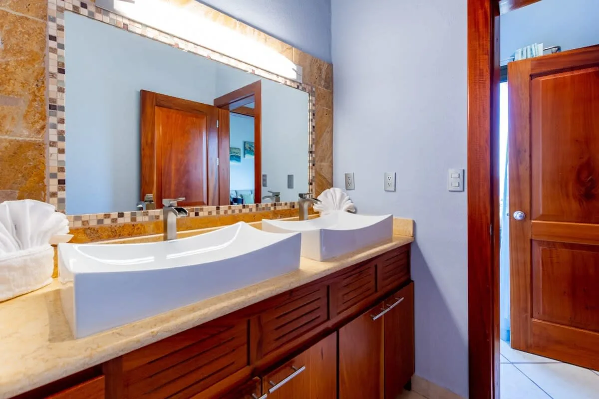 A bathroom vanity with two sinks sits beneath a large mirror.