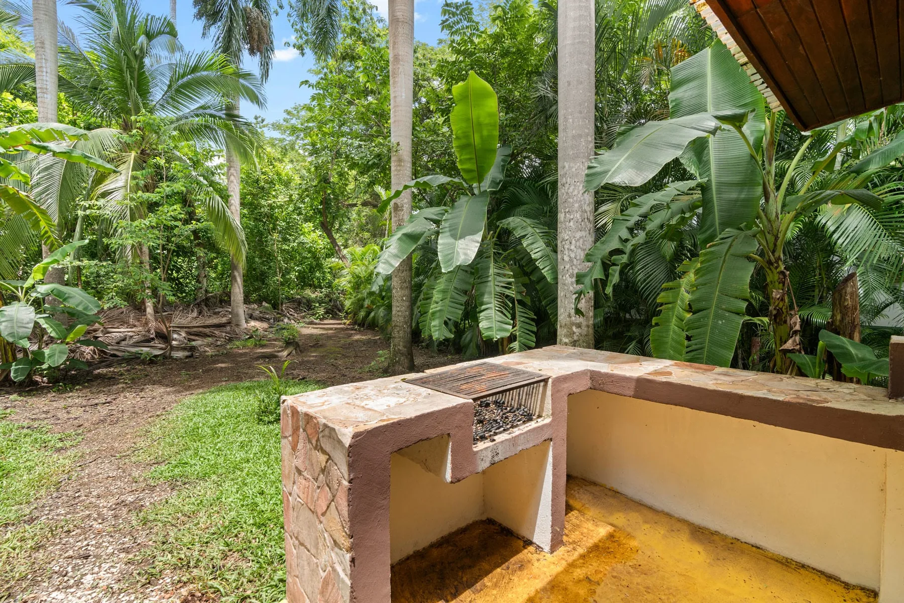 Shared amenity: An outdoor garden patio with a built-in counter surrounded by tropical plants.