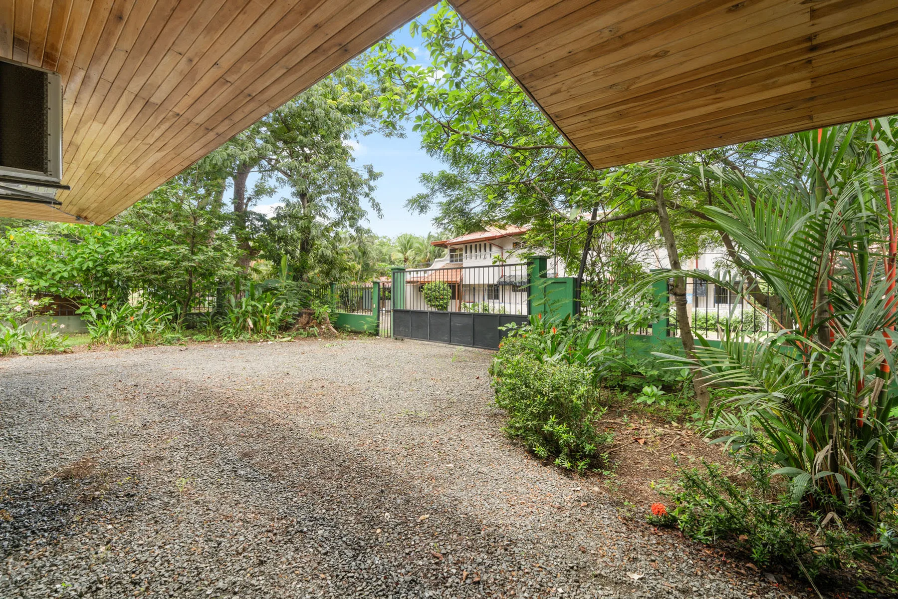 Shared amenity: A gravel driveway runs beneath a wooden canopy, surrounded by trees and shrubs.