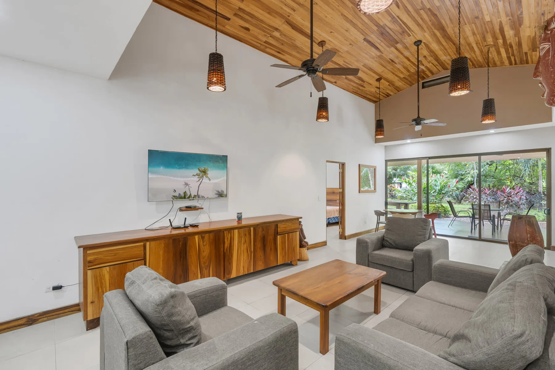 A living room with seating and a wooden coffee table beneath a wood-paneled ceiling.