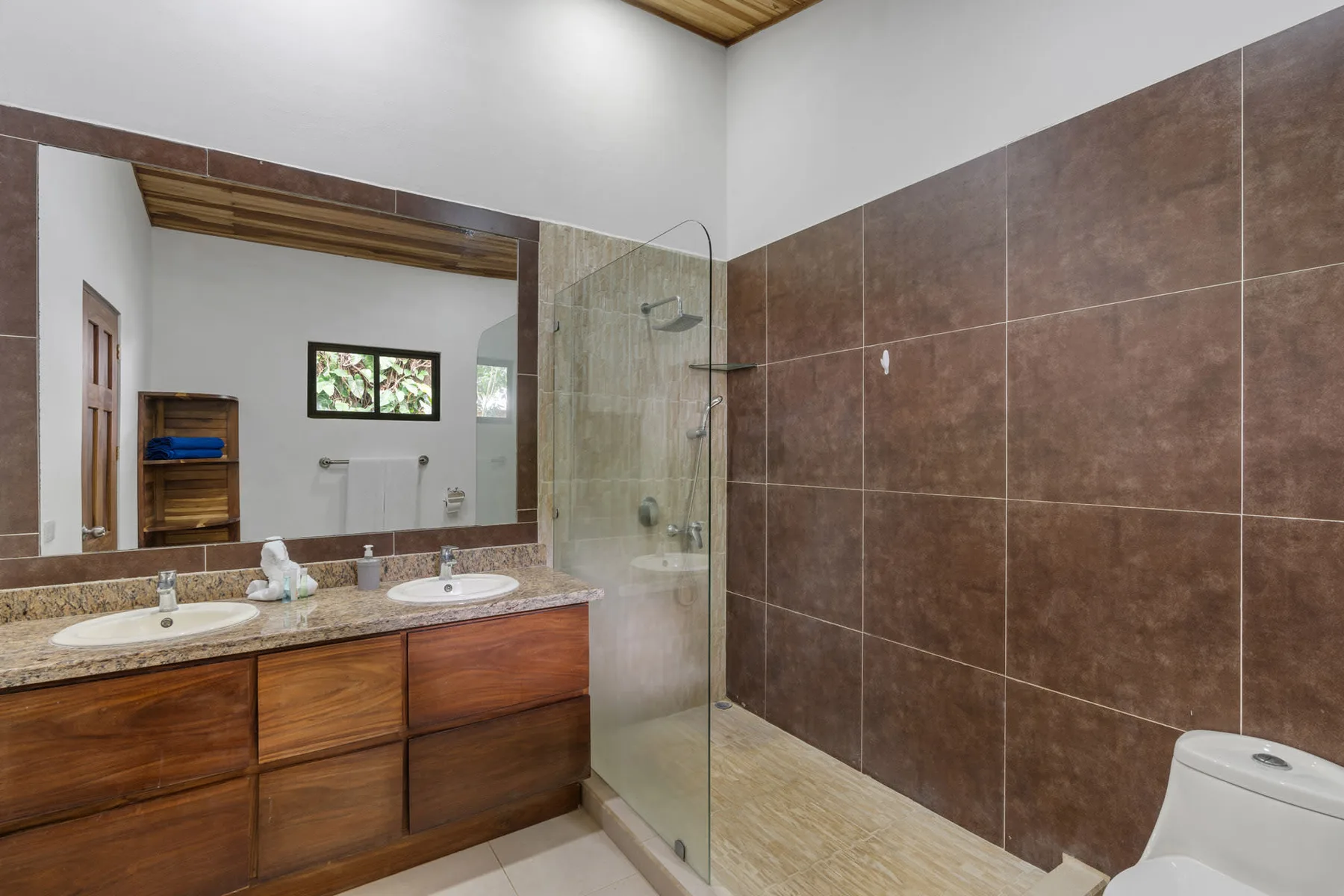 A bathroom vanity and sink sit beside a glass shower and tiled wall.