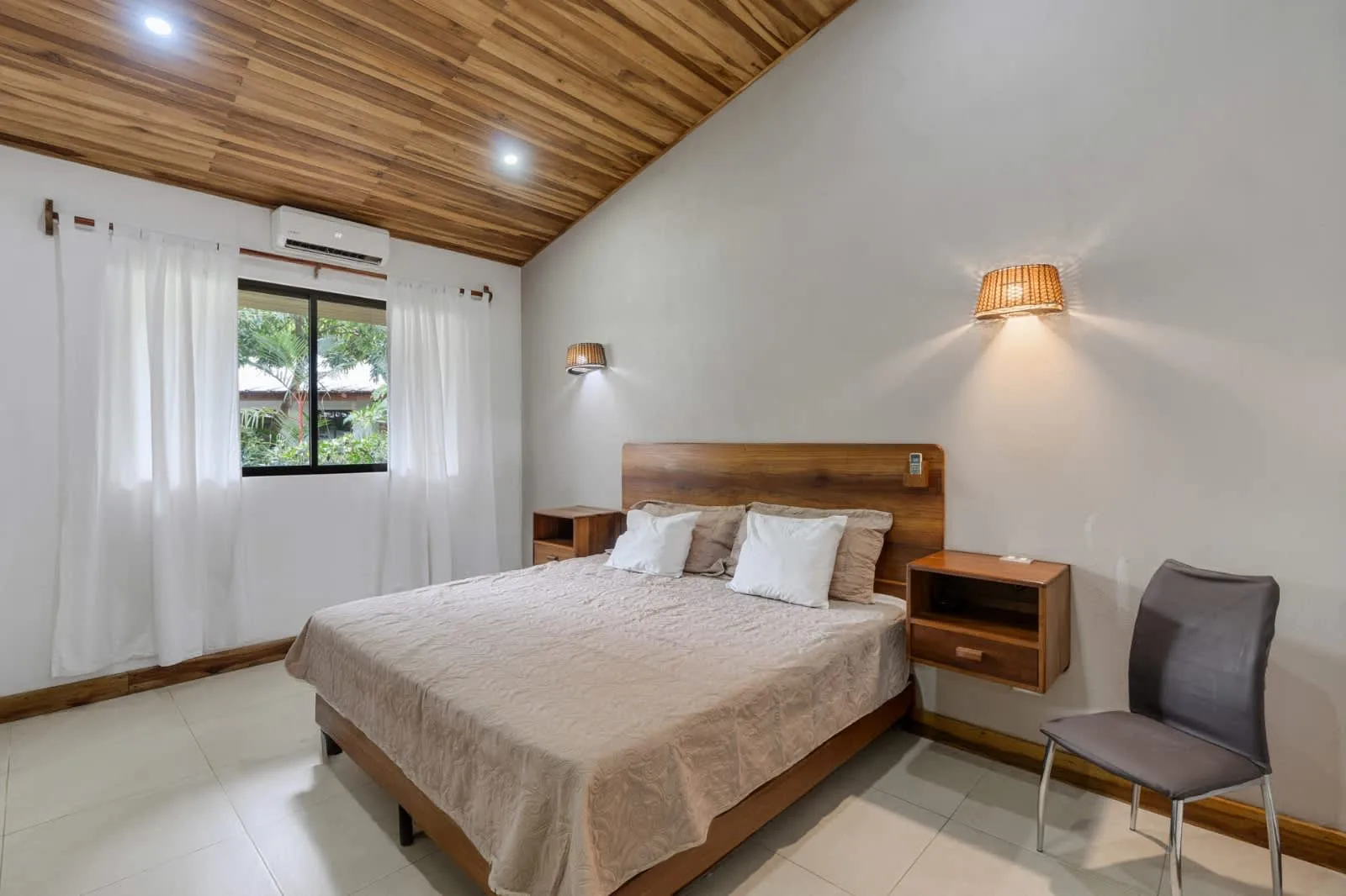 A bedroom with a bed, bedside tables, and a window with curtains.