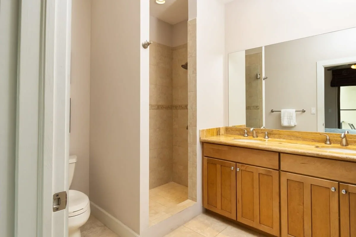 Un baño con un mueble de madera, un espejo amplio y una ducha.