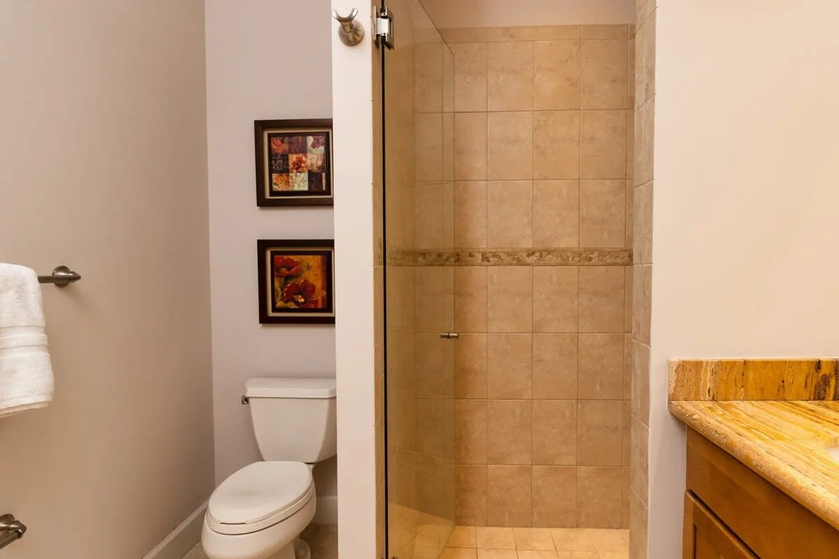 Un baño con ducha de azulejos, inodoro y tocador de madera.