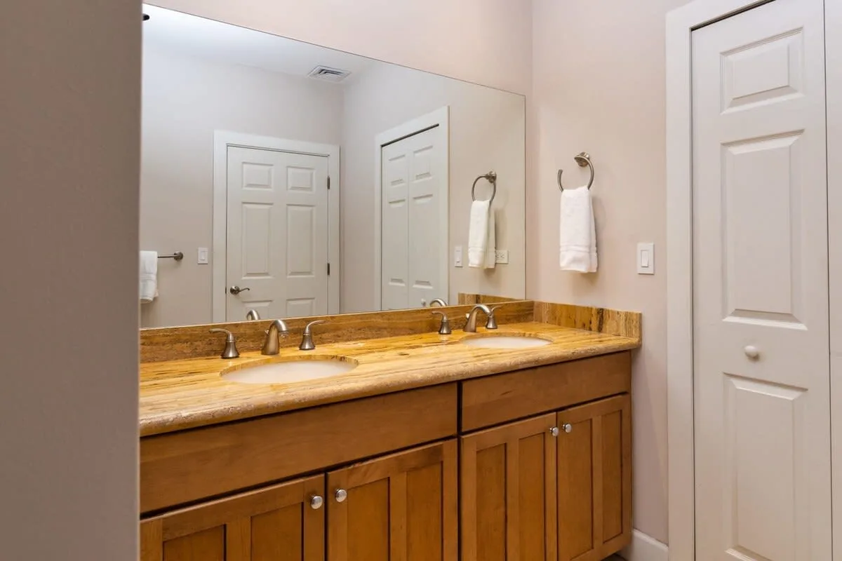 Un tocador de baño con un espejo amplio y gabinetes de madera.