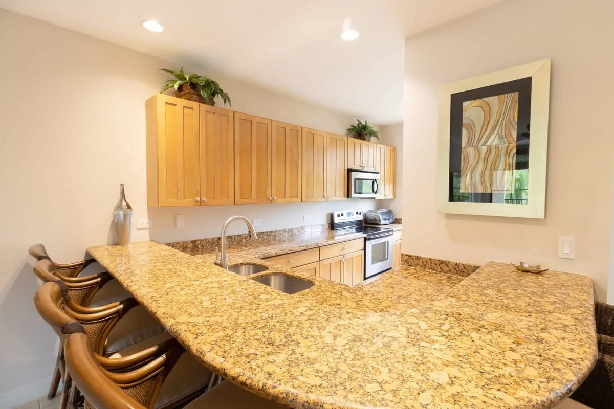 Una cocina luminosa con una gran encimera de granito y gabinetes de madera.