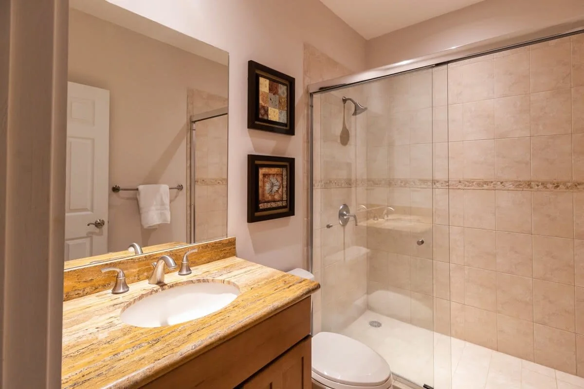 Un baño con lavabo de tocador y una ducha con mampara de vidrio.